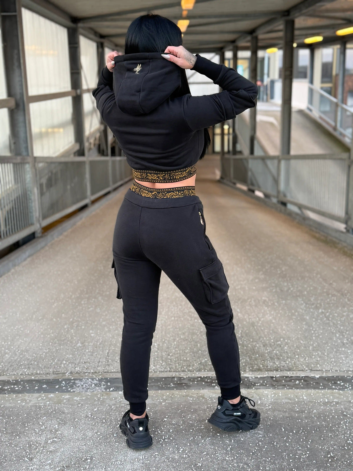 Model showing the back of the MVL Meander women's tracksuit with hands on the hood