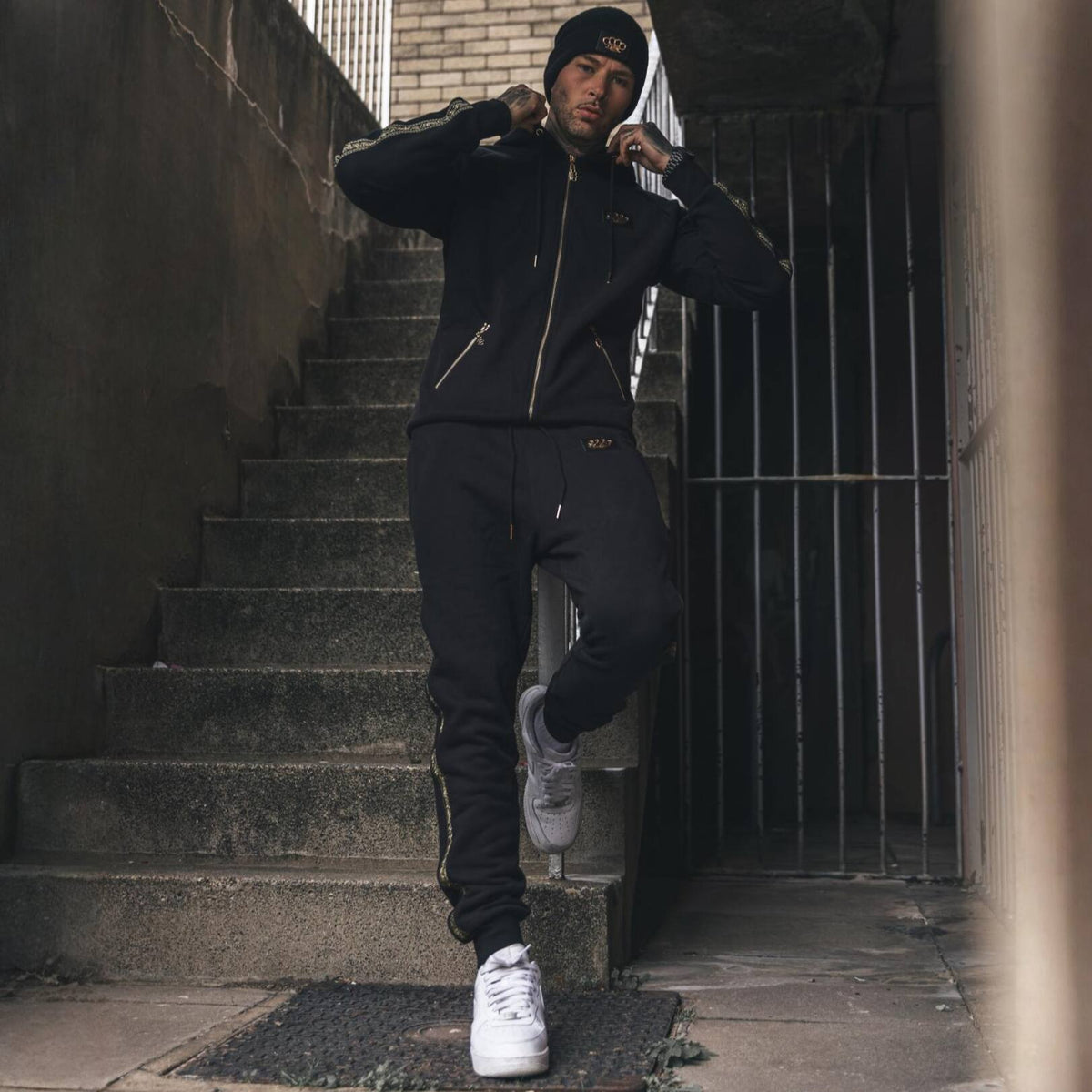 Mannequin en hoodie et jogging MVL Meander sur un escalier extérieur, avec baskets blanches