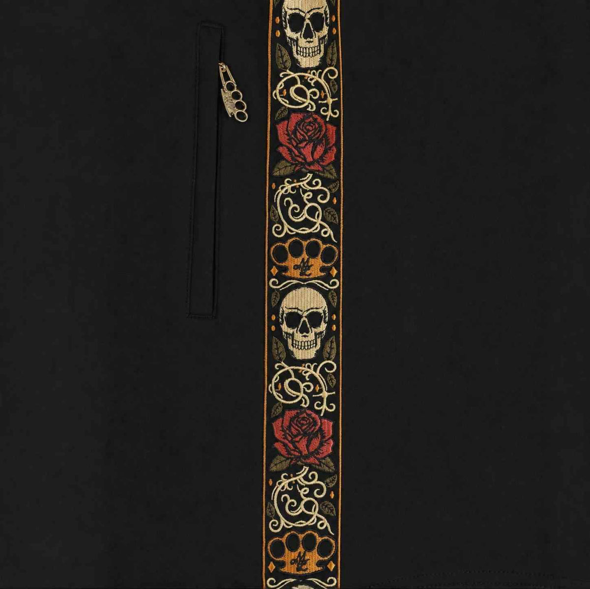 Close-up van de geborduurde Calavera band met skulls, rozen en MVL logo naast de zakrits