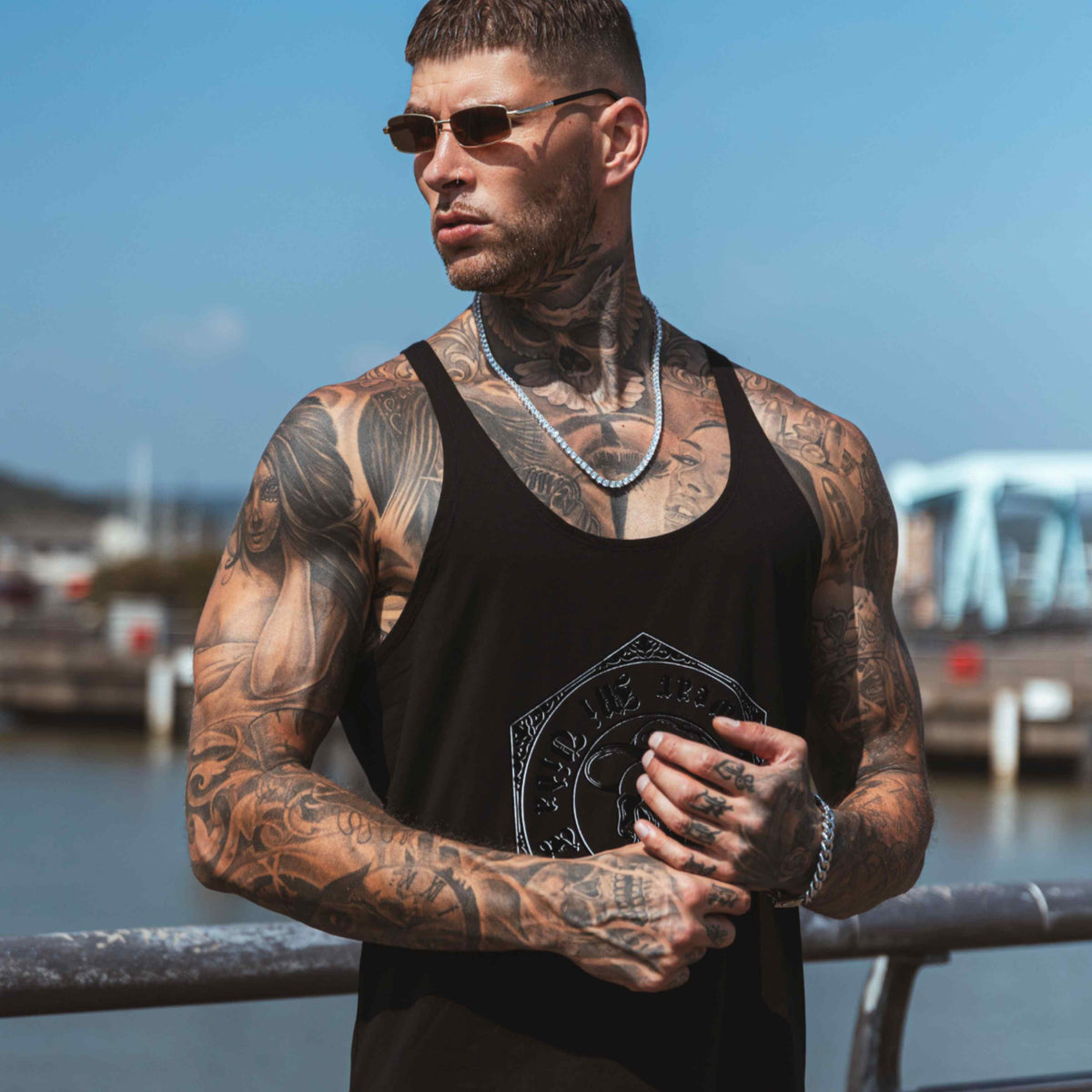 Débardeur MVL Original streetwear noir porté par un mannequin avec lunettes de soleil et chaîne argentée, devant