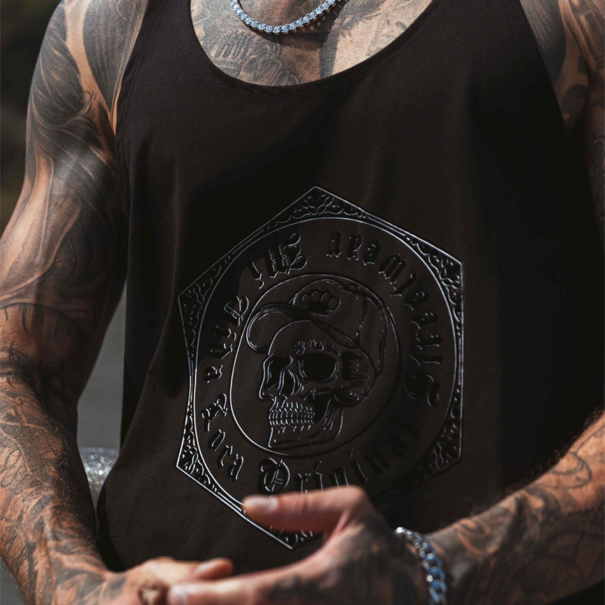 Gros plan de l'imprimé tête de mort 3D avec texte Original streetwear sur le débardeur MVL noir, porté
